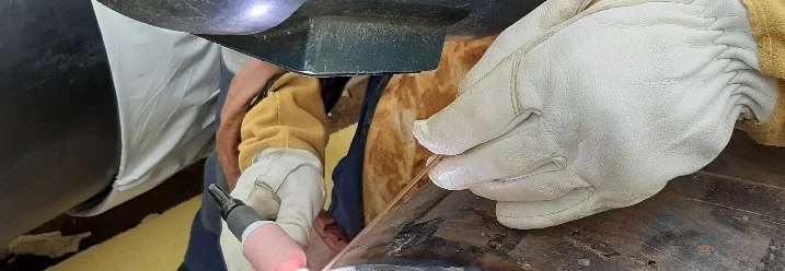 Person schweißt ein Rohr